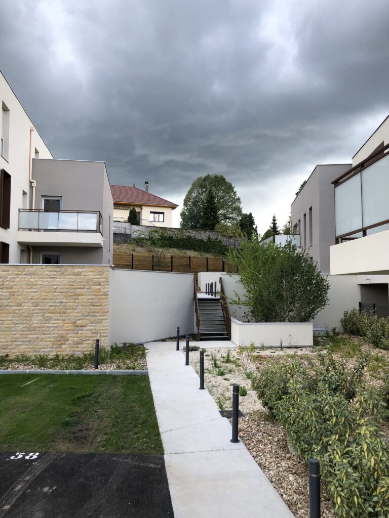 Cheminement paysager – Le perchoir paysage Cheminement piéton sinueux, massifs de plantes vivaces et mur en pierres dans une résidence à Morestel