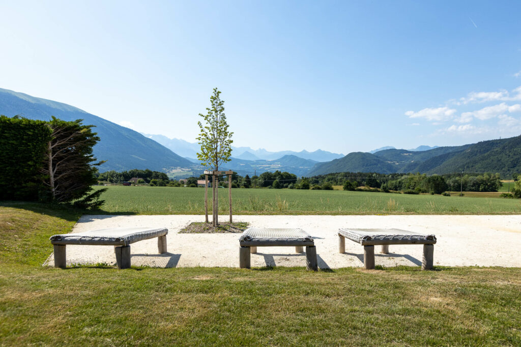 Mobilier urbain en bois et aménagement d'une aire de repos paysagère face aux montagnes à Sinard