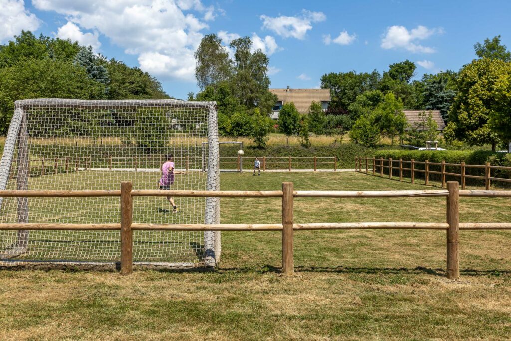 Terrain multisport en bois avec cage de football et clôture paysagère en bois à Sinard
